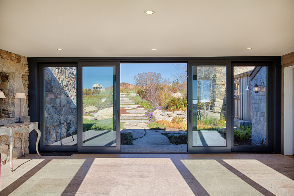 This is an example of an expansive beach style front door in Boston with concrete floors, a sliding front door, a glass front door and grey floor.
