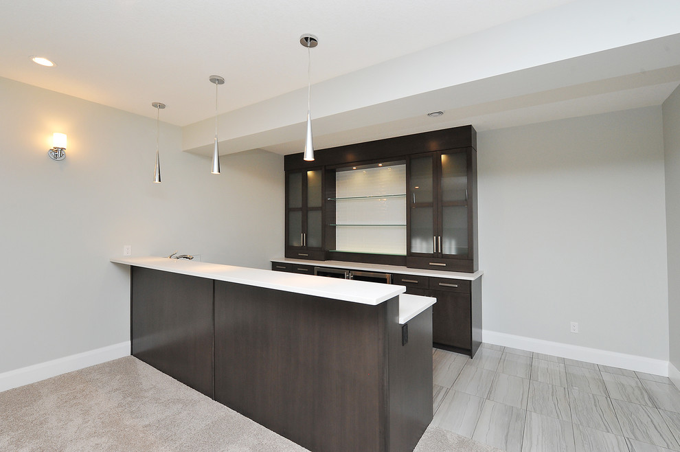 Photo of a mid-sized modern galley home bar in Calgary with flat-panel cabinets, dark wood cabinets, solid surface benchtops, porcelain floors, grey floor and white benchtop.