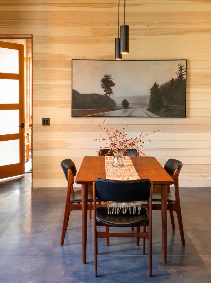 Example of a mountain style concrete floor, gray floor and wood wall dining room design in Portland Maine
