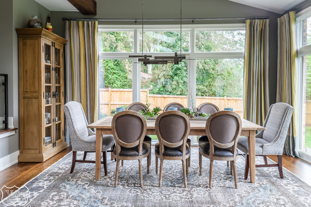 Large transitional medium tone wood floor and brown floor great room photo with gray walls, a corner fireplace and a stone fireplace