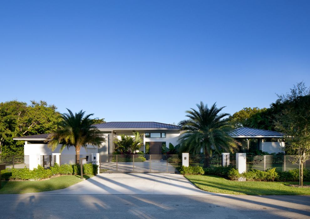 Imagen de fachada de casa blanca y gris tropical extra grande de una planta con revestimiento de piedra, tejado a cuatro aguas y tejado de metal