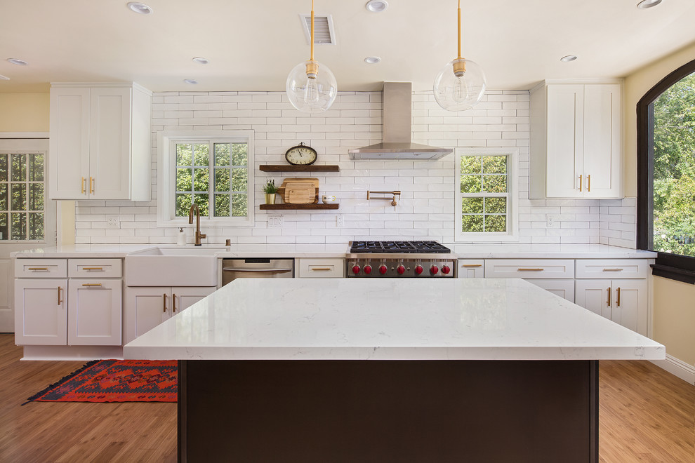 Design ideas for a mid-sized country single-wall open plan kitchen in Los Angeles with a farmhouse sink, shaker cabinets, white cabinets, quartz benchtops, white splashback, porcelain splashback, stainless steel appliances, light hardwood floors, with island, brown floor and yellow benchtop.