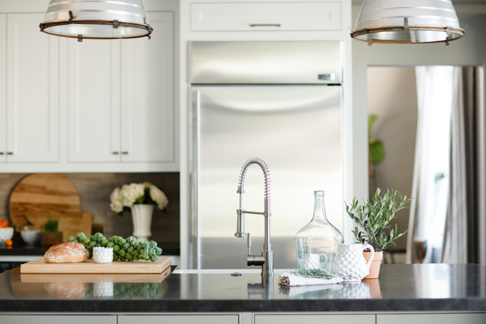 Inspiration for a large transitional l-shaped light wood floor open concept kitchen remodel in Orange County with a farmhouse sink, beaded inset cabinets, white cabinets, beige backsplash, stone tile backsplash, stainless steel appliances, gray walls and an island