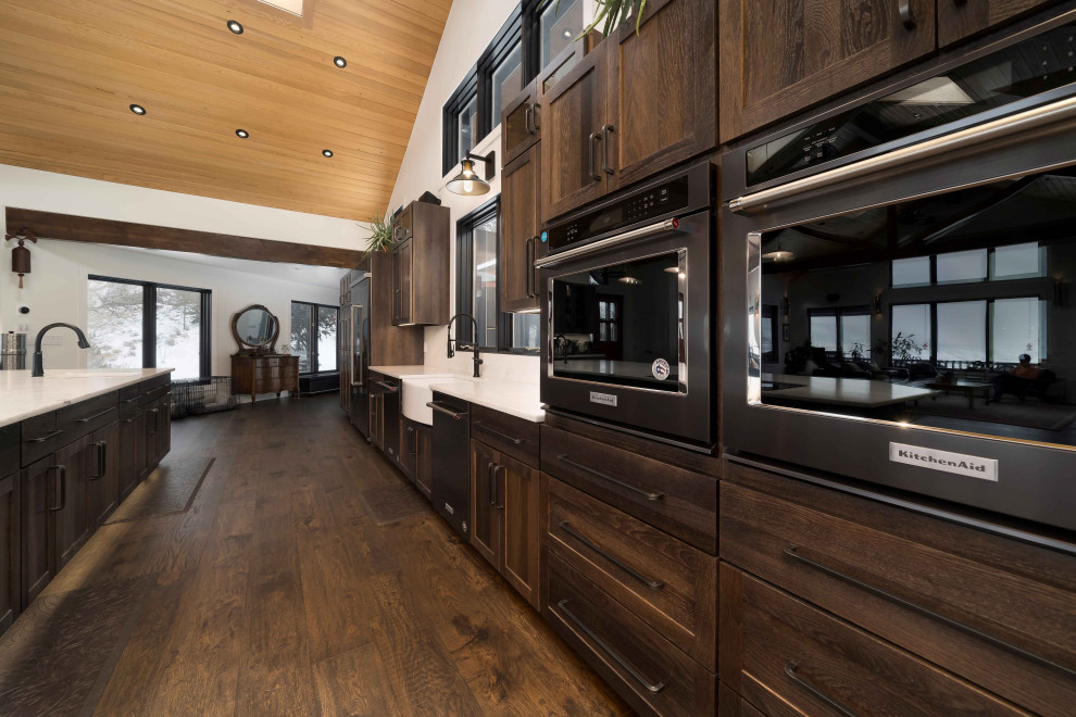 Inspiration for an expansive transitional single-wall open plan kitchen in Denver with a farmhouse sink, shaker cabinets, dark wood cabinets, marble benchtops, panelled appliances, dark hardwood floors, with island, brown floor, white benchtop and timber.