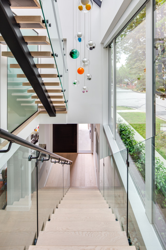 Example of a minimalist wooden straight open and glass railing staircase design in Vancouver