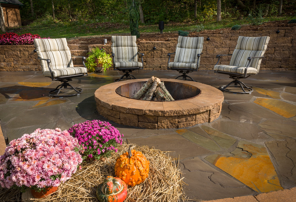 This is an example of a large contemporary side yard patio in Cincinnati with a fire feature, natural stone pavers and no cover.