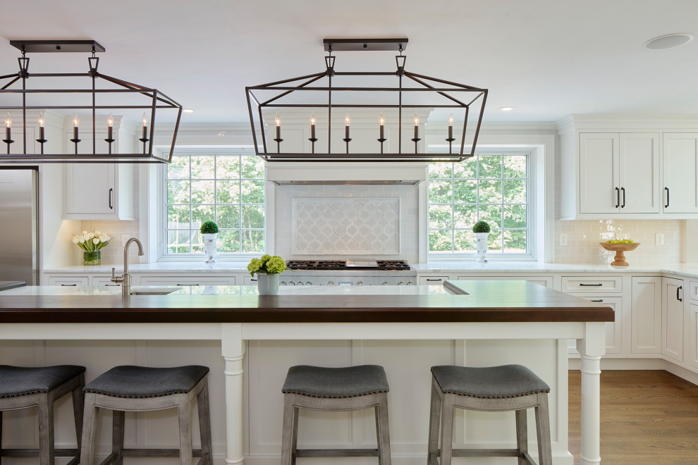 Design ideas for a large transitional l-shaped eat-in kitchen in Boston with an undermount sink, shaker cabinets, white cabinets, stainless steel appliances, medium hardwood floors, with island and brown floor.