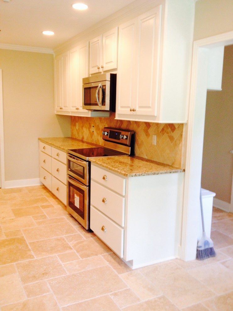 Inspiration for a mid-sized transitional galley ceramic tile enclosed kitchen remodel in Jackson with a double-bowl sink, raised-panel cabinets, white cabinets, granite countertops, brown backsplash, mosaic tile backsplash, stainless steel appliances and no island