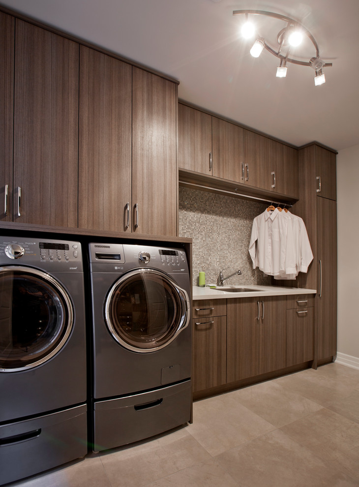 This is an example of a mid-sized contemporary single-wall utility room in Toronto with flat-panel cabinets, medium wood cabinets, beige walls and a side-by-side washer and dryer.