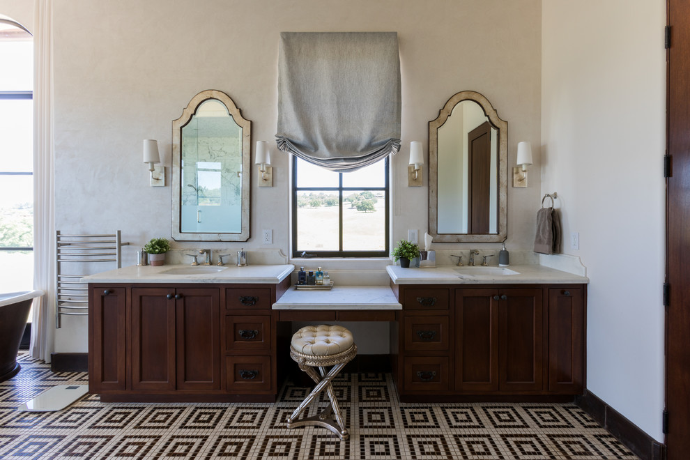 Photo of a mediterranean master bathroom in San Luis Obispo with shaker cabinets, dark wood cabinets, beige walls, an undermount sink, multi-coloured floor, beige benchtops and mosaic tile floors.