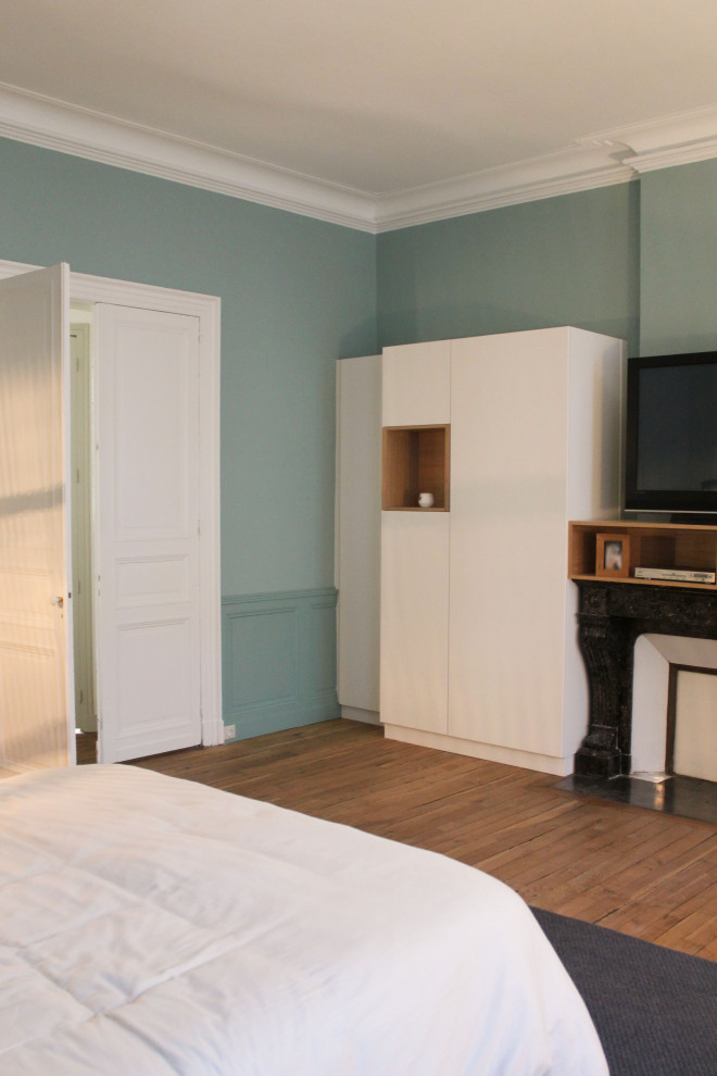 Пример оригинального дизайна: огромная хозяйская спальня в современном стиле с синими стенами, паркетным полом среднего тона, стандартным камином, фасадом камина из камня и панелями на стенах
