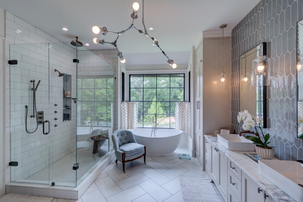 This is an example of a large master bathroom in Atlanta with shaker cabinets, grey cabinets, a freestanding tub, a corner shower, a two-piece toilet, multi-coloured tile, ceramic tile, white walls, porcelain floors, a vessel sink, marble benchtops, white floor, a hinged shower door, multi-coloured benchtops, a niche, a double vanity and a built-in vanity.