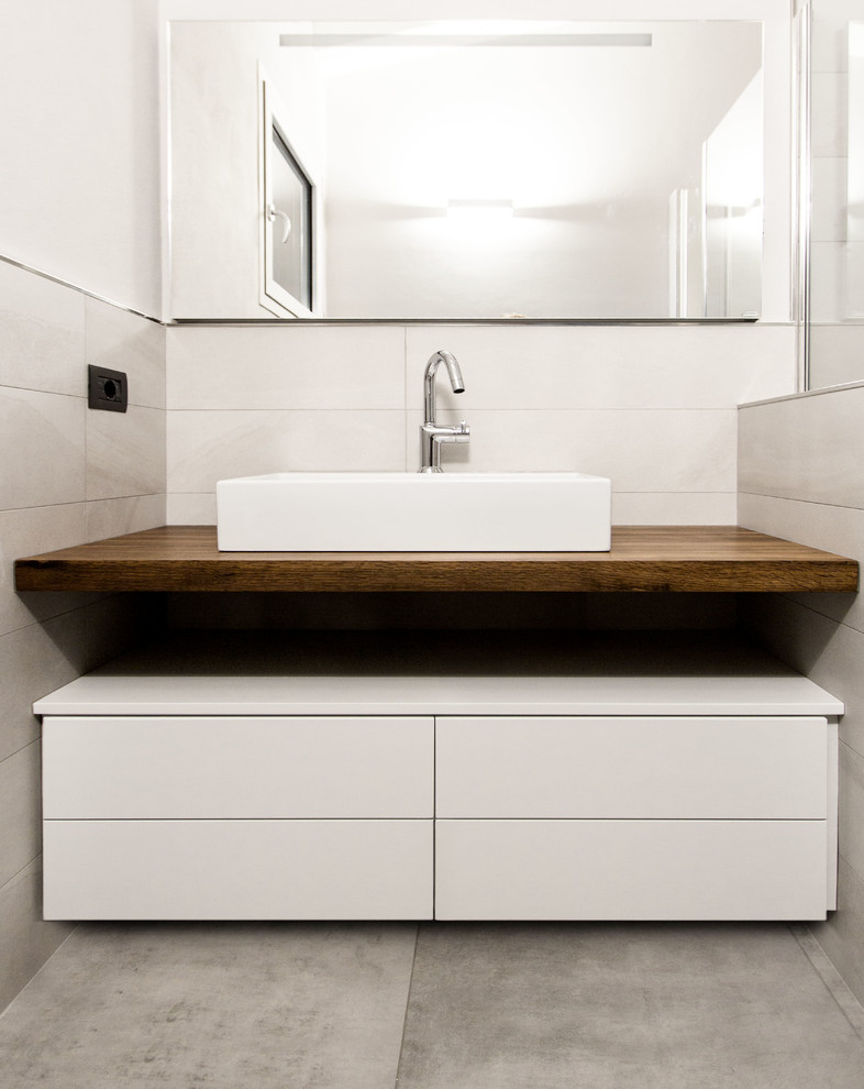 Inspiration for a small contemporary master bathroom in Milan with flat-panel cabinets, white cabinets, gray tile, porcelain tile, grey walls, porcelain floors, a trough sink and wood benchtops.