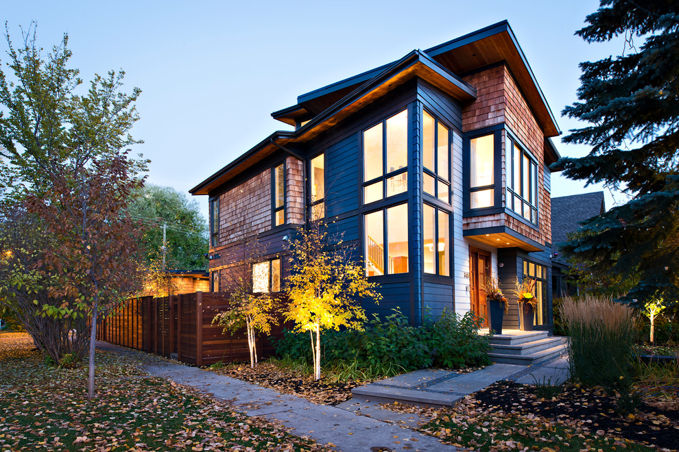This is an example of a large contemporary two-storey grey exterior in Calgary with vinyl siding and a flat roof.