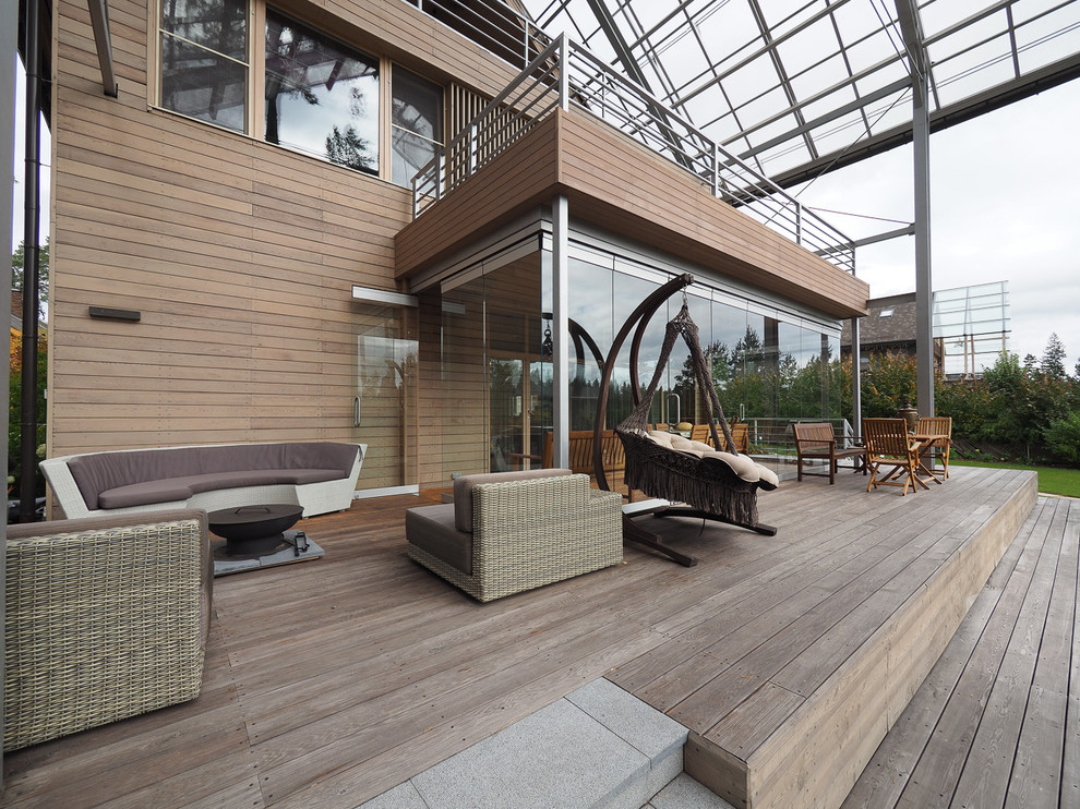 Inspiration for a mid-sized contemporary backyard deck in Moscow with a roof extension.