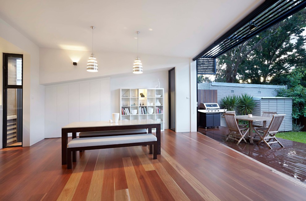 Photo of a small contemporary open plan dining in Melbourne with white walls, medium hardwood floors and brown floor.
