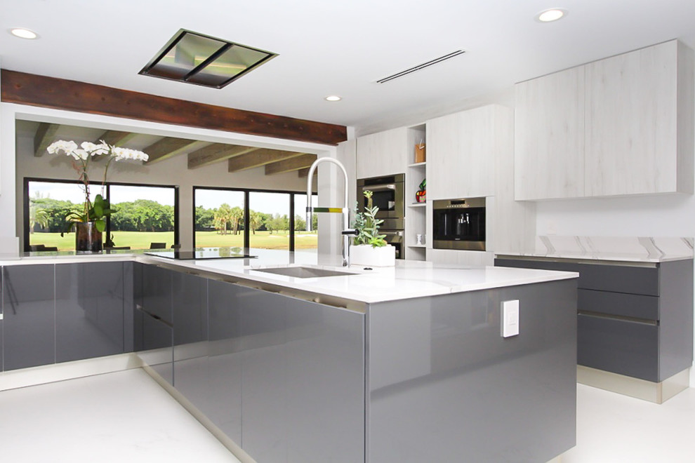 This is an example of a large modern u-shaped kitchen in Other with an undermount sink, flat-panel cabinets, grey cabinets, stainless steel appliances, with island, white floor and white benchtop.