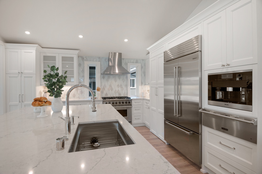 Transitional vaulted ceiling kitchen pantry photo in San Francisco with recessed-panel cabinets, white cabinets, quartz countertops, white backsplash, glass tile backsplash, stainless steel appliances and white countertops