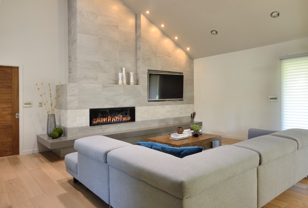 Photo of a large modern open concept family room in Sacramento with beige walls, light hardwood floors, a ribbon fireplace, a stone fireplace surround and a built-in media wall.