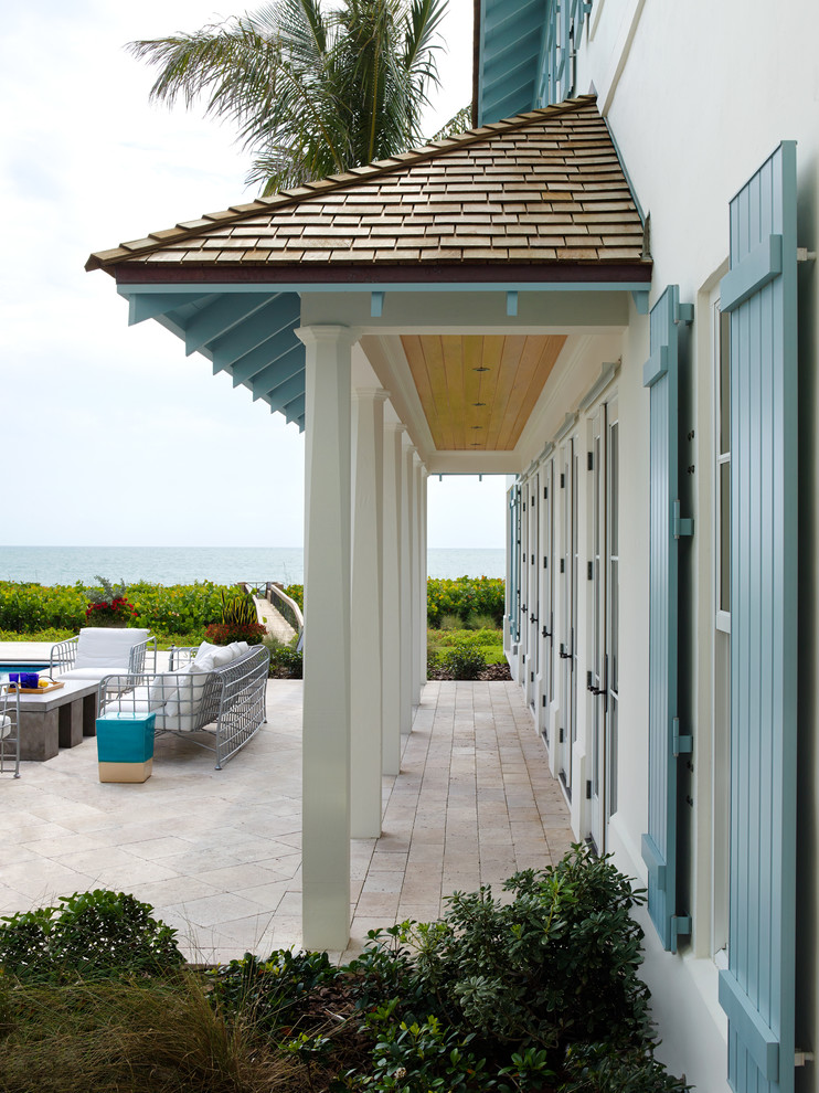Inspiration for a mid-sized traditional backyard patio in Miami with natural stone pavers and a roof extension.