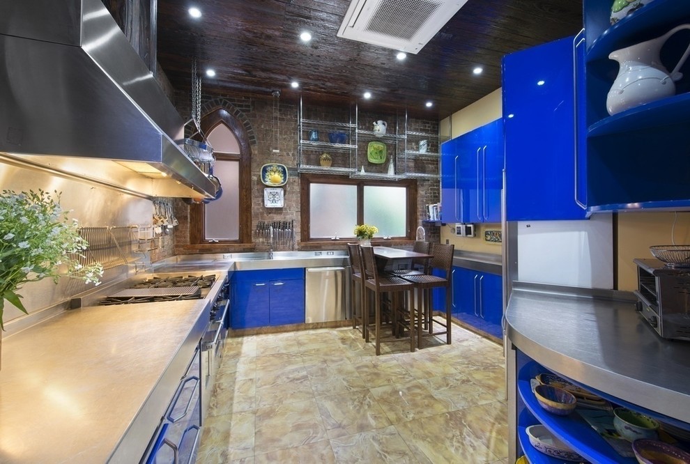 This is an example of an expansive u-shaped kitchen in New York with an undermount sink, flat-panel cabinets, blue cabinets, stainless steel benchtops, stainless steel appliances and marble floors.