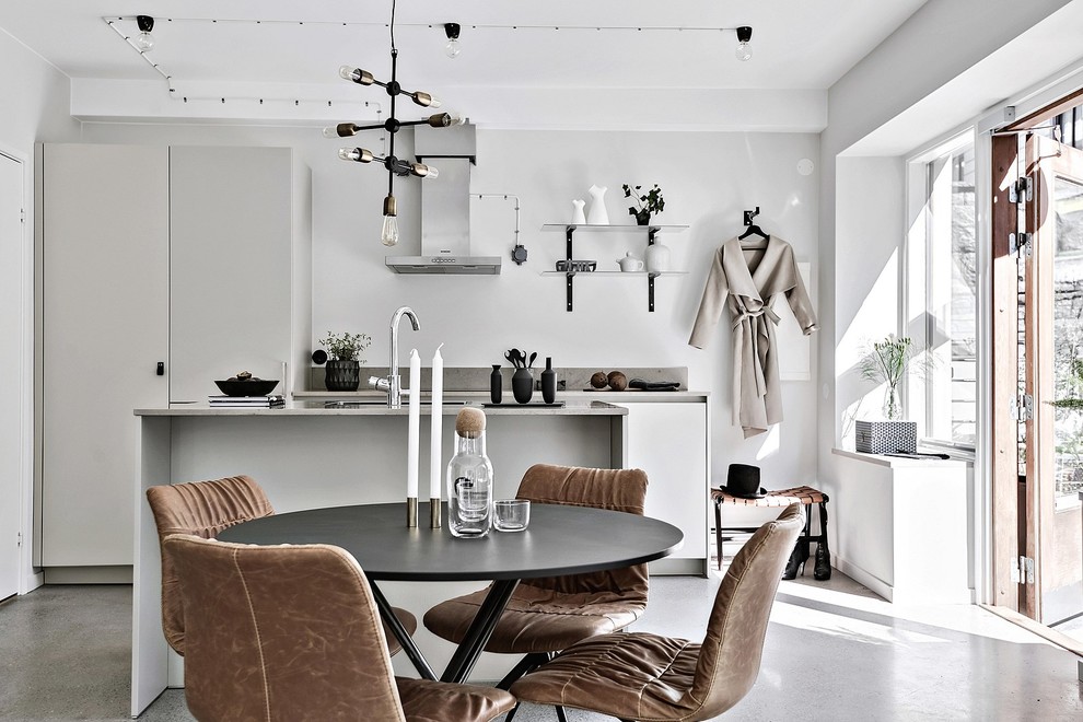 This is an example of a mid-sized scandinavian galley eat-in kitchen in Gothenburg with flat-panel cabinets, white cabinets, stainless steel appliances, concrete floors, with island, a single-bowl sink and marble benchtops.