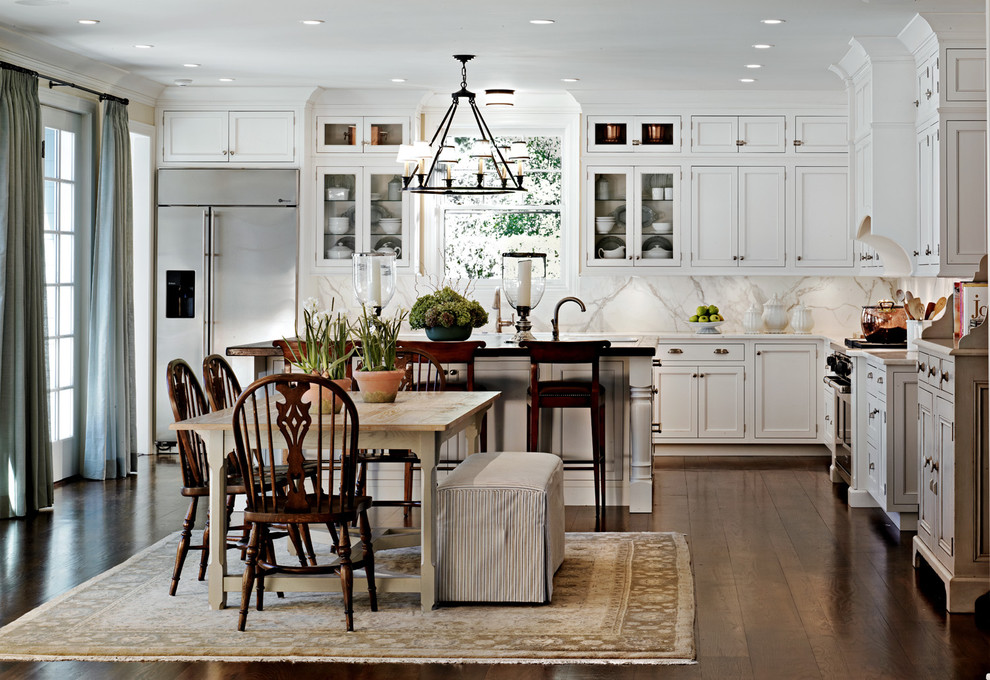This is an example of a traditional l-shaped eat-in kitchen in Detroit with stainless steel appliances, recessed-panel cabinets, white cabinets, white splashback and marble splashback.