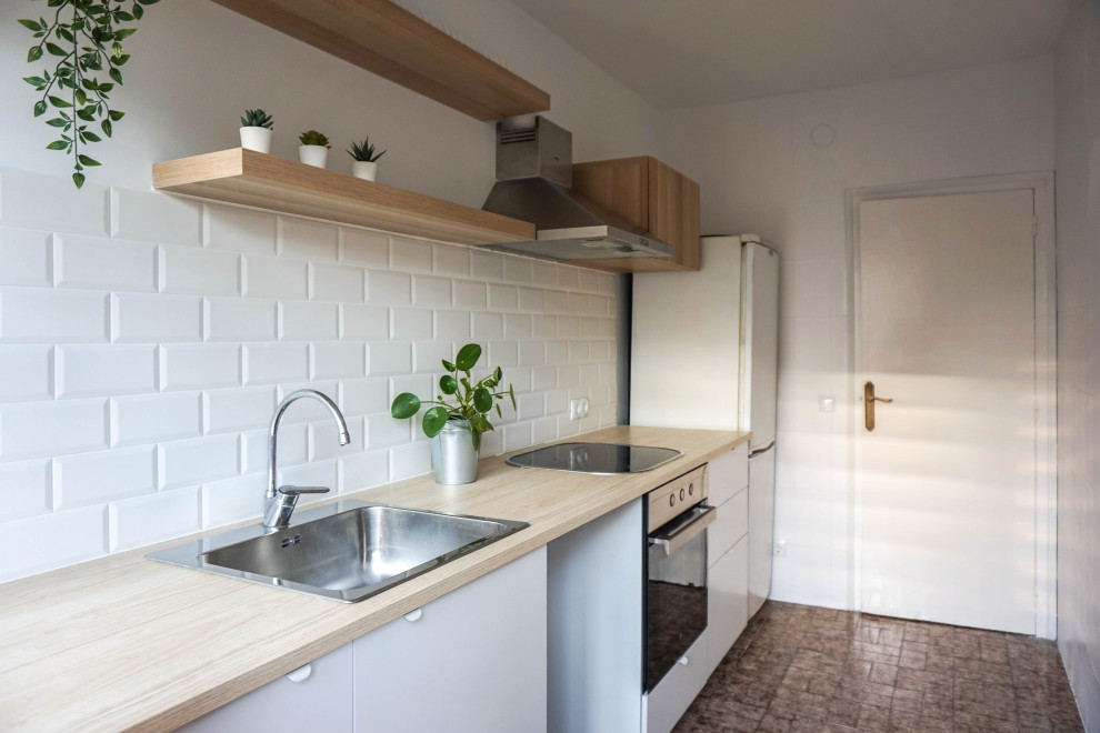 Mid-sized scandinavian single-wall separate kitchen in Barcelona with a single-bowl sink, flat-panel cabinets, white cabinets, laminate benchtops, white splashback, ceramic splashback, black appliances, ceramic floors, no island, brown floor and beige benchtop.