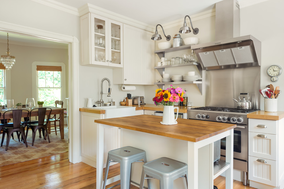 Mid-sized country l-shaped light wood floor kitchen photo in Boston with shaker cabinets, white cabinets, wood countertops, an island, a farmhouse sink and stainless steel appliances