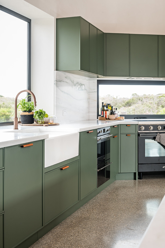 Design ideas for a large contemporary l-shaped open plan kitchen in Melbourne with a farmhouse sink, shaker cabinets, green cabinets, marble benchtops, white splashback, marble splashback, black appliances, concrete floors, with island, grey floor and white benchtop.
