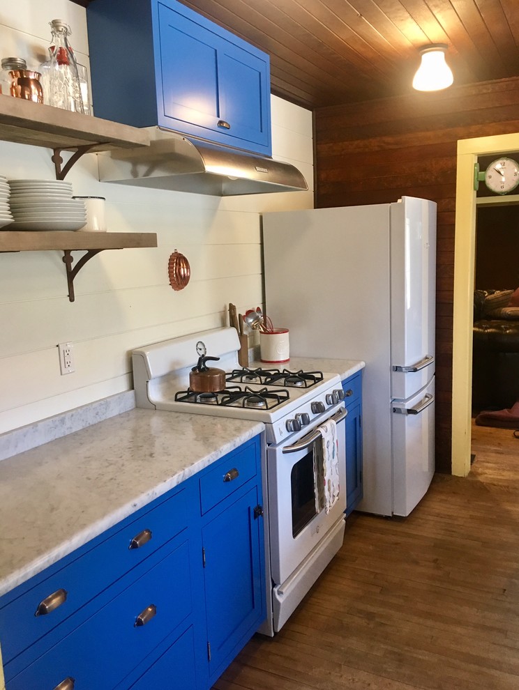 Mountain style kitchen photo with blue cabinets, white appliances and an island