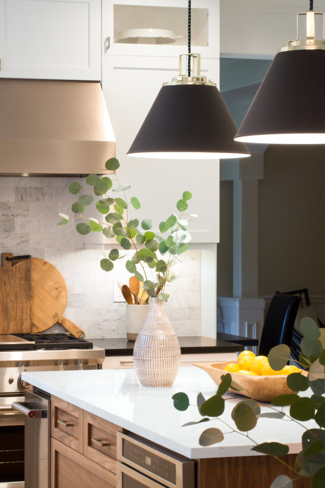 Example of a mid-sized transitional l-shaped light wood floor and brown floor eat-in kitchen design in Seattle with an undermount sink, shaker cabinets, white cabinets, quartz countertops, multicolored backsplash, marble backsplash, stainless steel appliances and an island