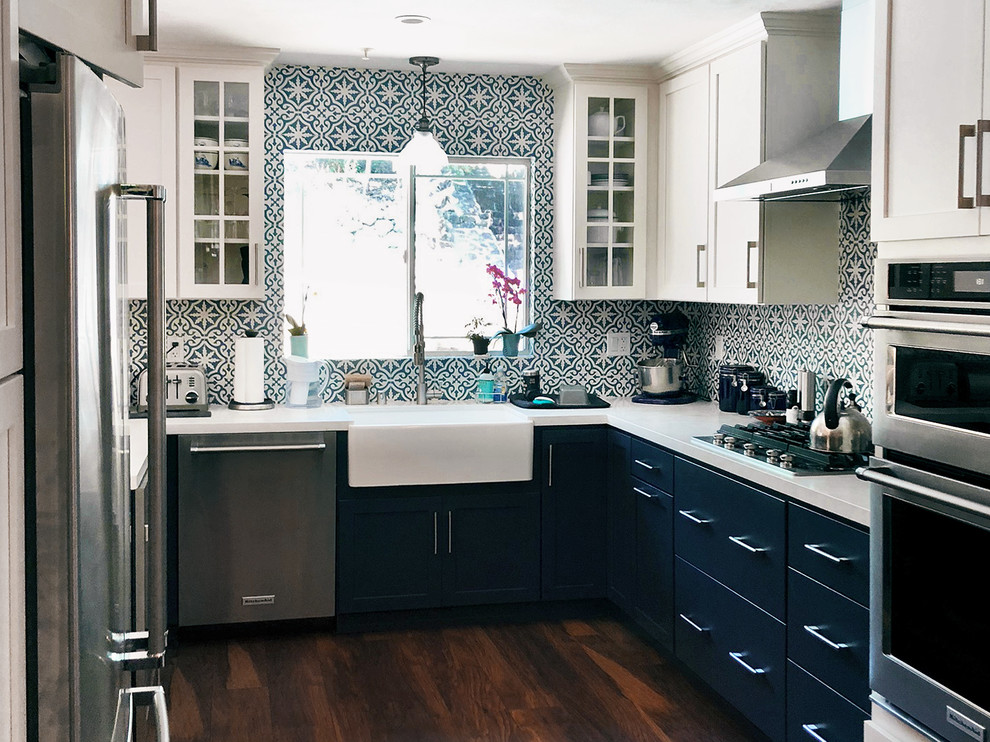 Mid-sized eclectic u-shaped separate kitchen in New York with a farmhouse sink, shaker cabinets, blue cabinets, blue splashback, porcelain splashback, stainless steel appliances, medium hardwood floors, brown floor, white benchtop, onyx benchtops and no island.