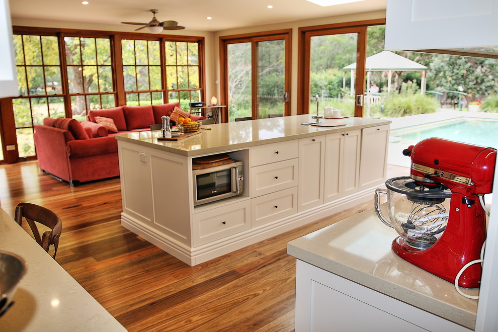 Design ideas for a large traditional l-shaped kitchen pantry in Sydney with a drop-in sink, shaker cabinets, white cabinets, quartz benchtops, brown splashback, glass sheet splashback, stainless steel appliances, medium hardwood floors and with island.