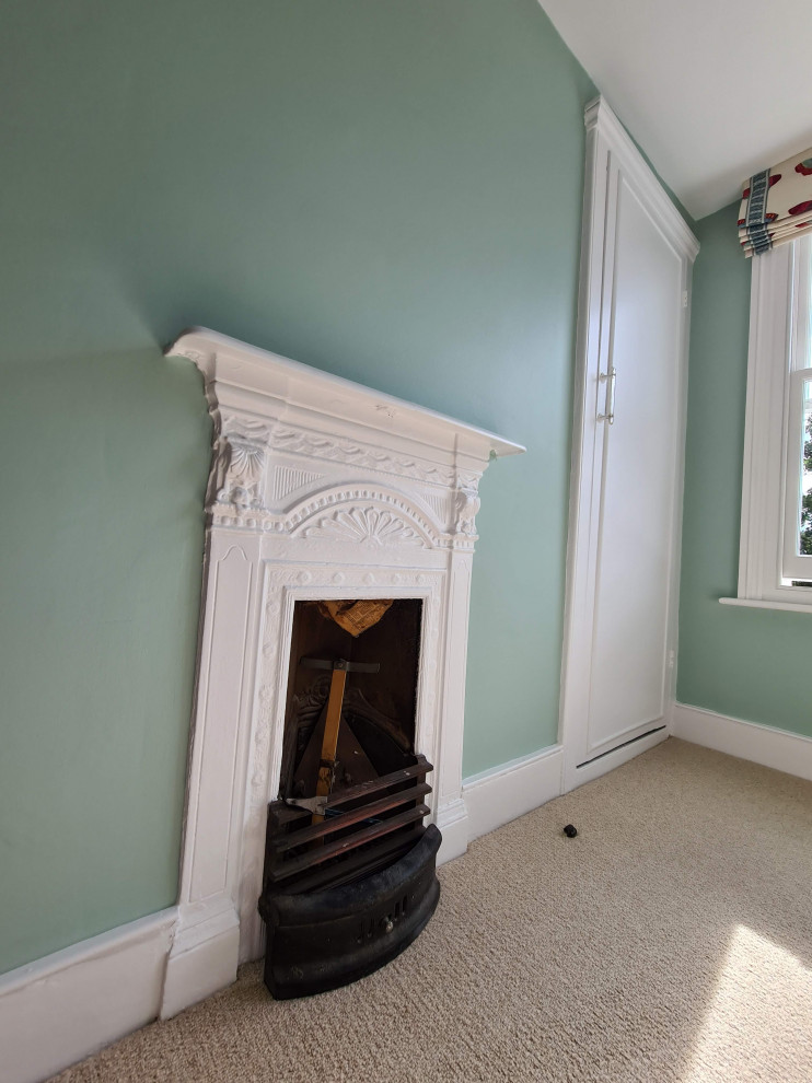 Inspiration for a medium sized classic guest bedroom in London with green walls, carpet, a standard fireplace, a metal fireplace surround, beige floors, a drop ceiling and a chimney breast.