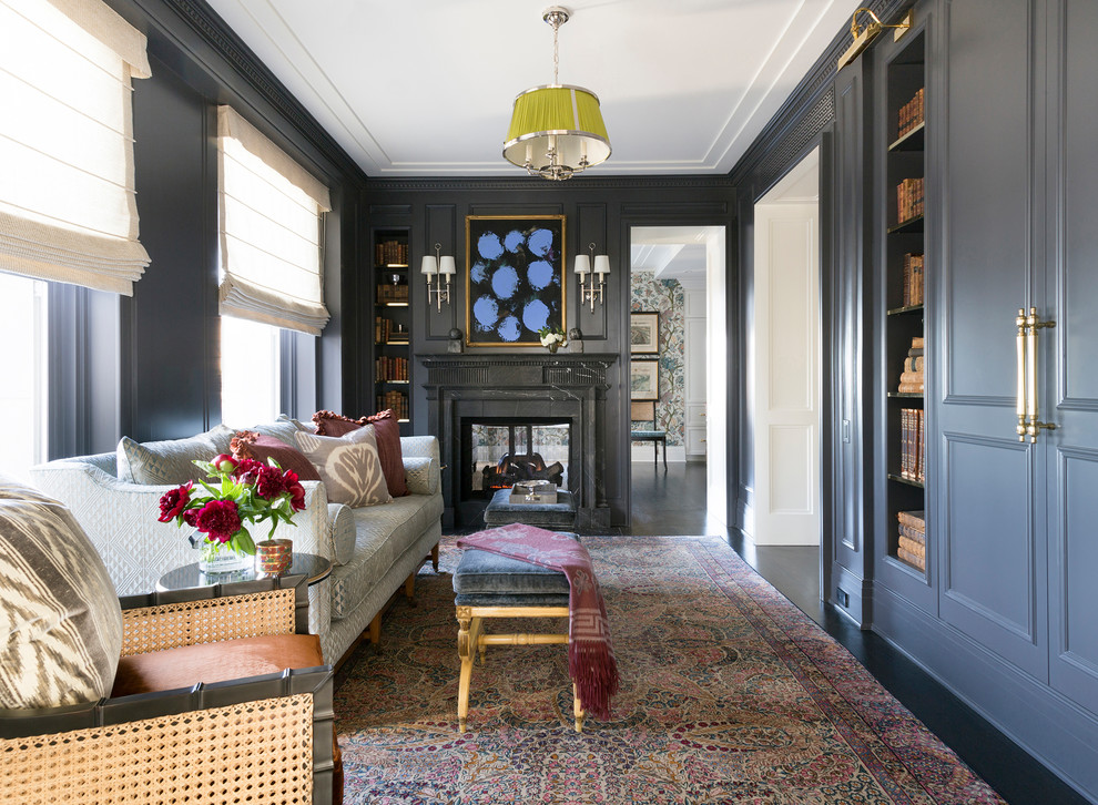 Inspiration for a large transitional home office in Chicago with a library, blue walls, dark hardwood floors, a standard fireplace, a plaster fireplace surround and brown floor.