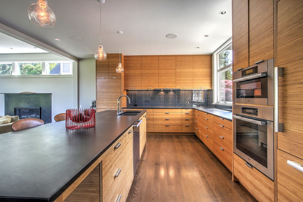 Expansive contemporary l-shaped open plan kitchen in Seattle with an undermount sink, medium wood cabinets, solid surface benchtops, grey splashback, glass tile splashback, stainless steel appliances, medium hardwood floors and with island.