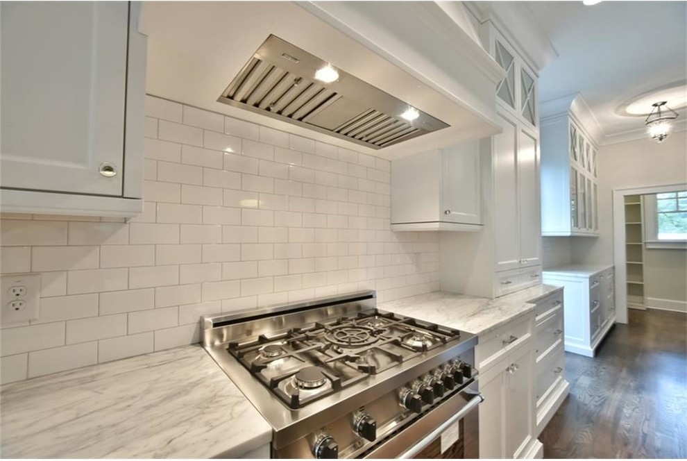 Kitchen - transitional dark wood floor kitchen idea in Atlanta with shaker cabinets, white cabinets, marble countertops, white backsplash, subway tile backsplash and stainless steel appliances