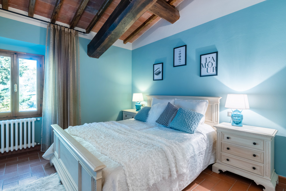 Foto di una camera da letto mediterranea con pareti blu, pavimento in terracotta, pavimento arancione, travi a vista e abbinamento di mobili antichi e moderni
