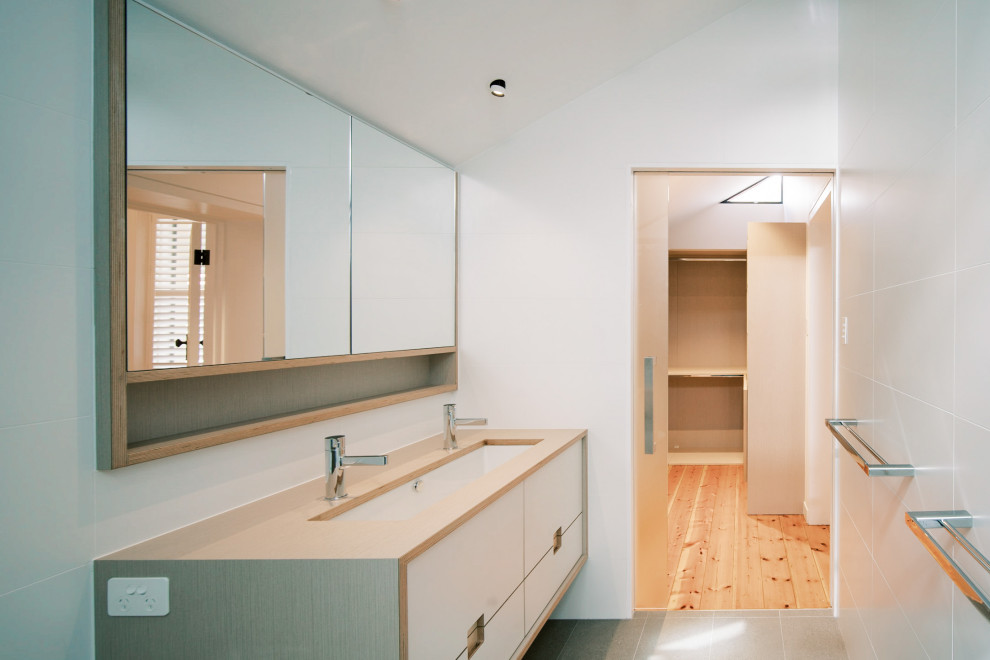 Inredning av ett modernt litet beige beige en-suite badrum, med luckor med infälld panel, skåp i ljust trä, en dubbeldusch, en bidé, vit kakel, porslinskakel, vita väggar, klinkergolv i porslin, ett undermonterad handfat, laminatbänkskiva, grått golv och dusch med skjutdörr