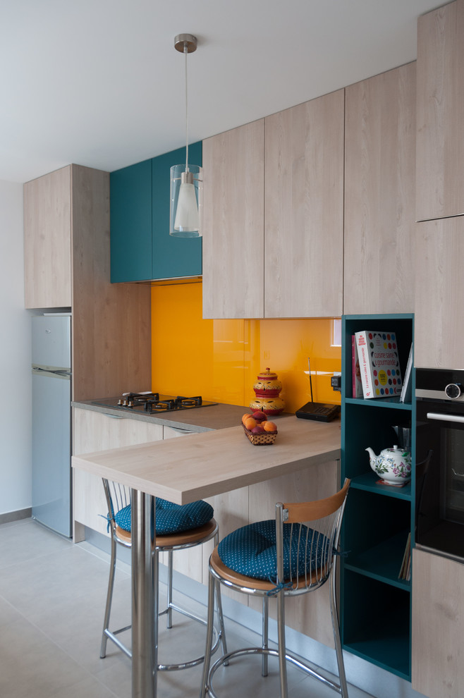 Mid-sized contemporary galley separate kitchen in Lyon with an integrated sink, beaded inset cabinets, light wood cabinets, laminate benchtops, orange splashback, glass sheet splashback, stainless steel appliances, ceramic floors, no island, grey floor and grey benchtop.