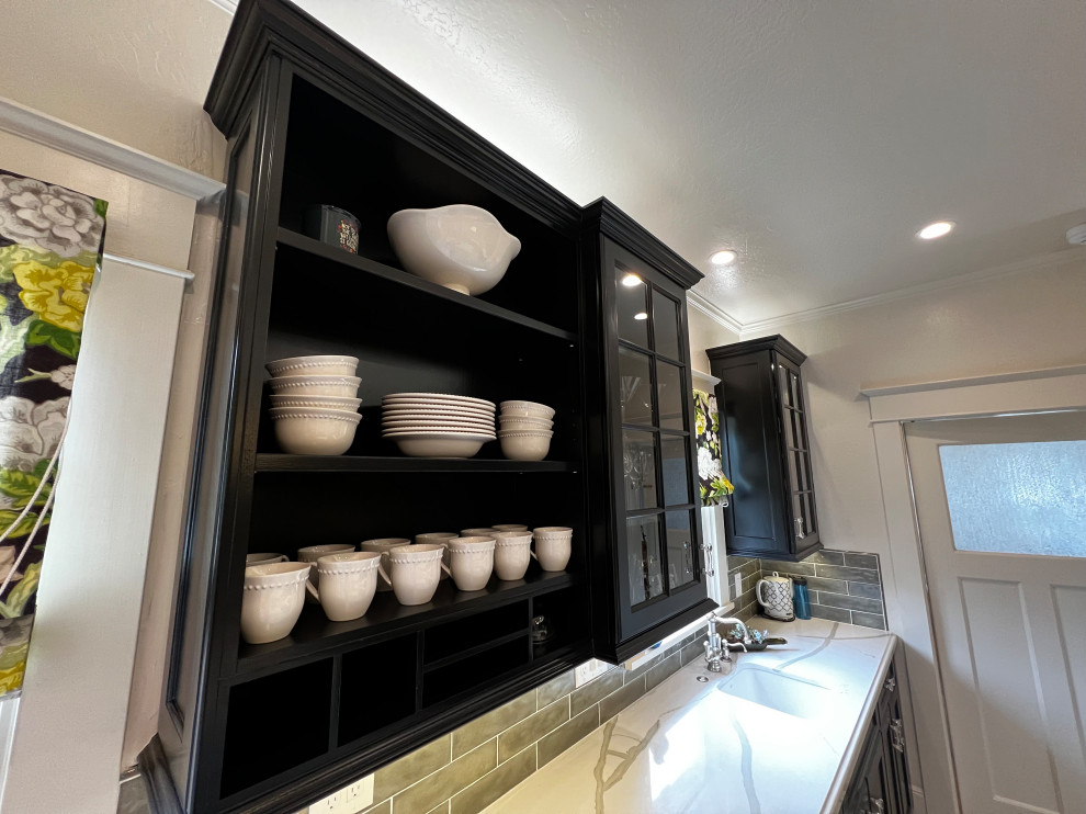 Design ideas for a large arts and crafts u-shaped kitchen in San Francisco with a farmhouse sink, flat-panel cabinets, black cabinets, quartz benchtops, green splashback, ceramic splashback, stainless steel appliances, porcelain floors, with island, black floor and white benchtop.
