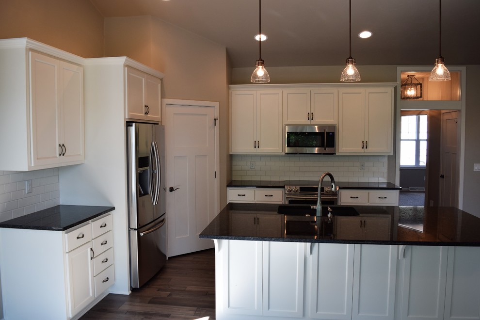 Inspiration for a mid-sized medium tone wood floor open concept kitchen remodel with white cabinets, granite countertops, subway tile backsplash, stainless steel appliances and an island