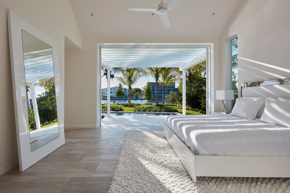 This is an example of a large contemporary master bedroom in Miami with white walls, light hardwood floors and no fireplace.