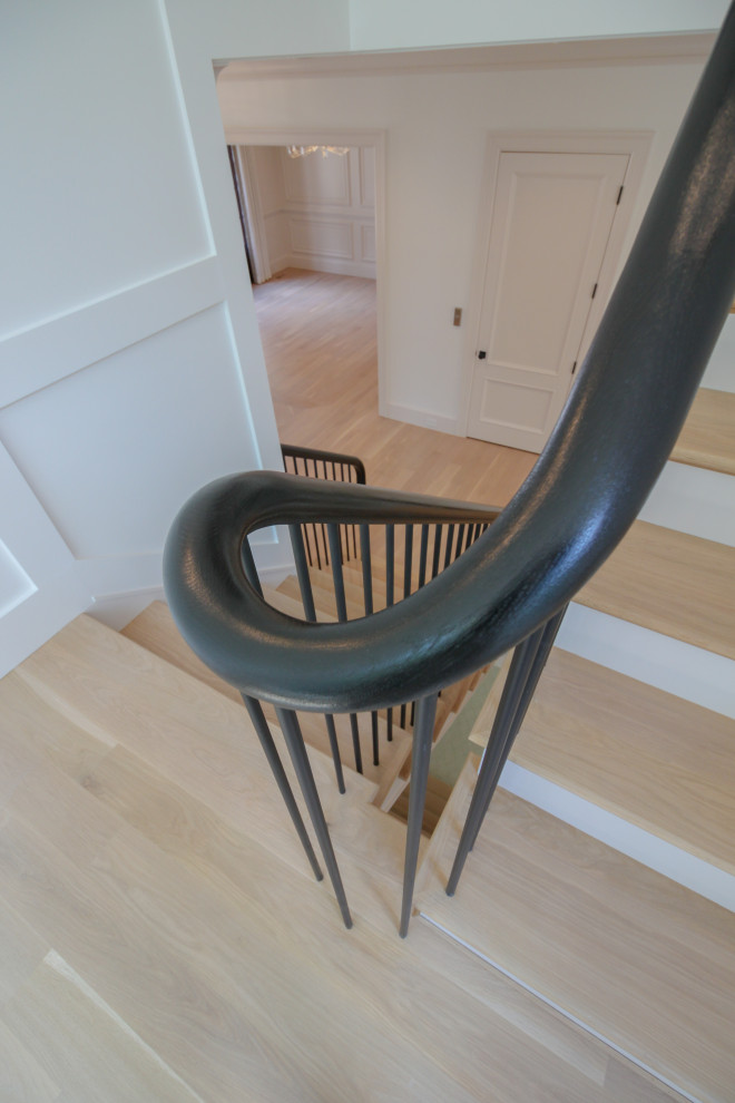 Imagen de escalera en U moderna grande con escalones de madera, contrahuellas de madera pintada, barandilla de varios materiales y boiserie