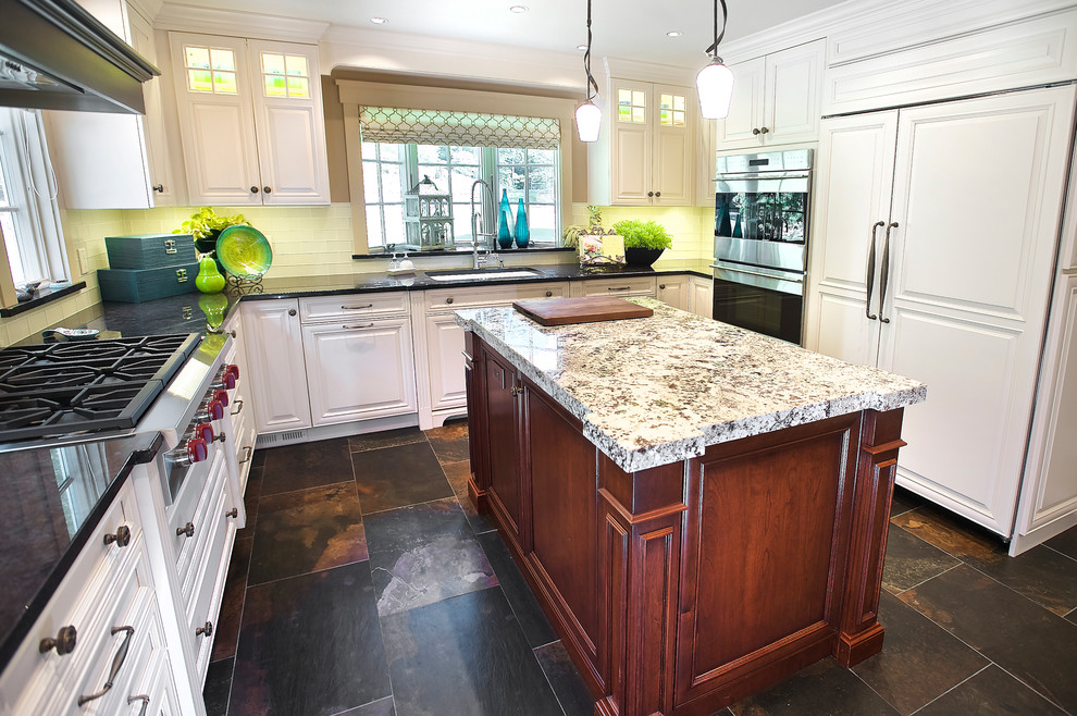 Inspiration for a large traditional u-shaped eat-in kitchen in Las Vegas with multiple islands, an undermount sink, beaded inset cabinets, white cabinets, quartzite benchtops, white splashback, glass tile splashback, stainless steel appliances, slate floors and brown floor.