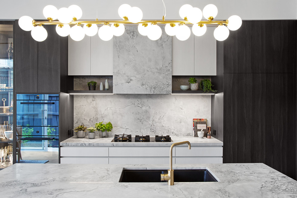 Inspiration for a contemporary galley kitchen in Melbourne with an undermount sink, flat-panel cabinets, black cabinets, grey splashback, stone slab splashback, with island and grey benchtop.