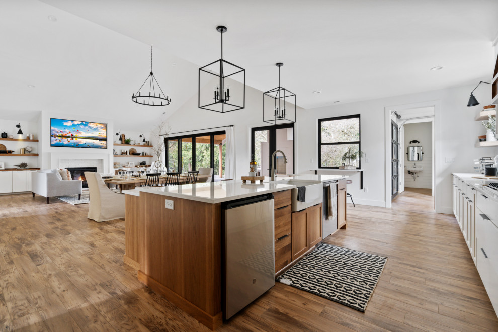 Photo of a large country u-shaped open plan kitchen in Portland with a farmhouse sink, shaker cabinets, medium wood cabinets, quartzite benchtops, white splashback, ceramic splashback, stainless steel appliances, laminate floors, with island, white benchtop and vaulted.