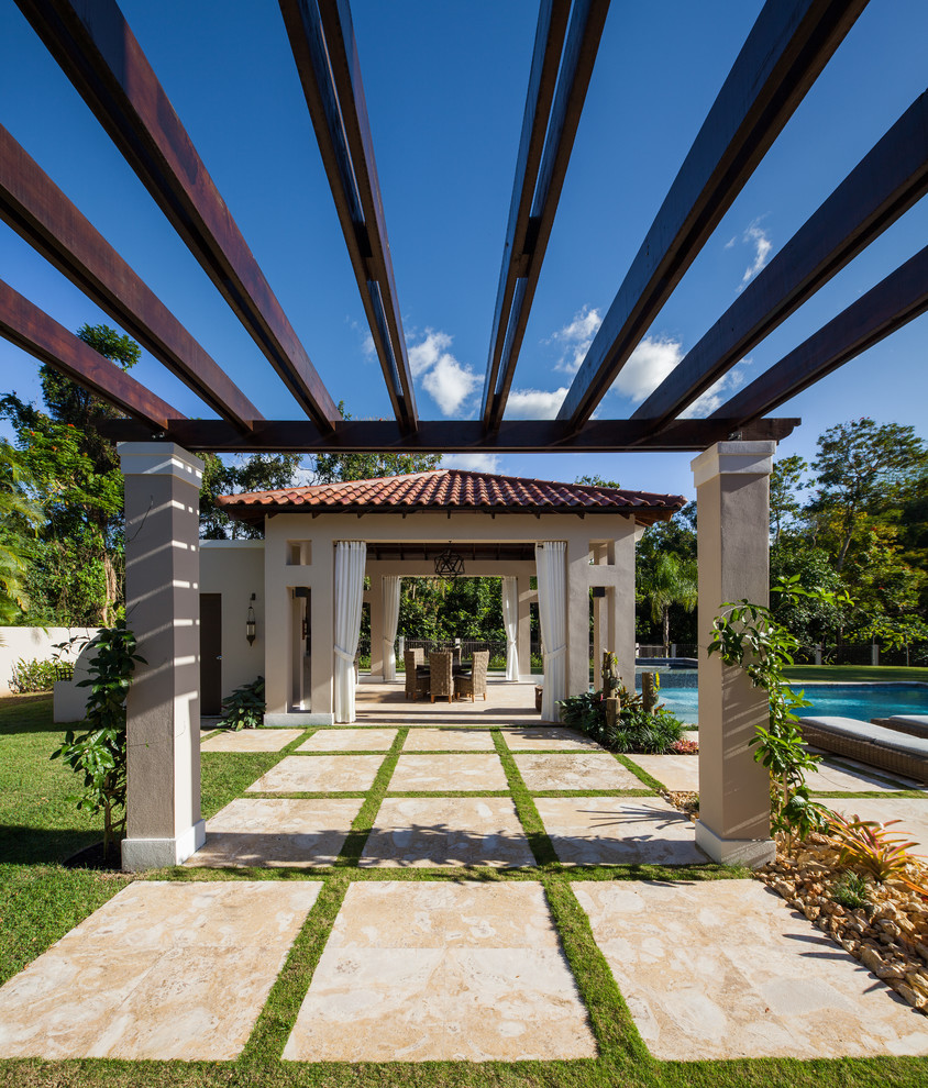 This is an example of a large mediterranean backyard patio in Other with a pergola, an outdoor kitchen and natural stone pavers.