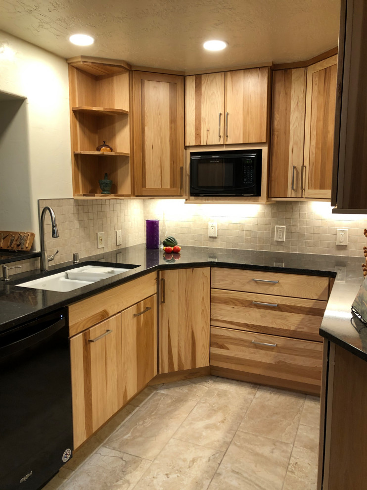 This is an example of a small contemporary u-shaped kitchen in Albuquerque with an undermount sink, flat-panel cabinets, light wood cabinets, quartz benchtops, grey splashback, porcelain splashback, black appliances, porcelain floors and black benchtop.